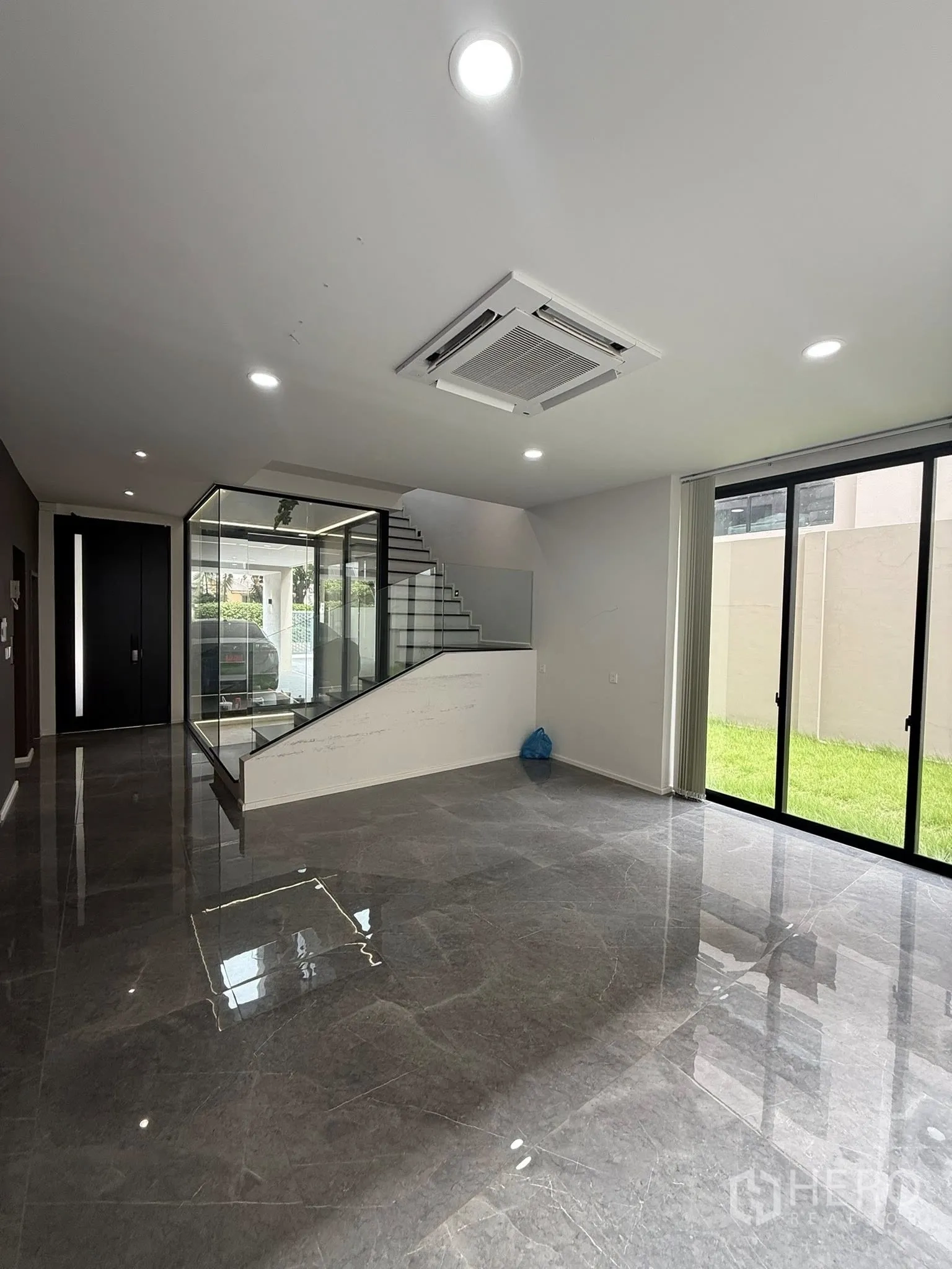 สำนักงานที่บ้าน ให้เช่าหรือขายในLat Phrao, Bangkok - พื้นที่อเนกประสงค์ชั้นล่าง พื้นหินอ่อน แอร์คาสเซ็ต และประตูกระจกสไลด์เปิดสู่สวนหญ้า.