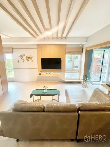 独立式住宅 出租在Prawet, Bangkok - 明亮客厅，L型沙发、壁挂电视与木格栅天花