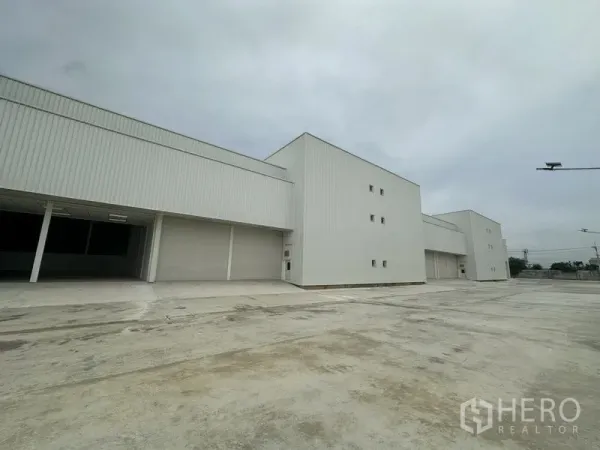 โรงงาน ให้เช่าในPathum Thani - มุมด้านข้างอาคารคลังสินค้าพร้อมประตูม้วนขนาดใหญ่และทางรถบรรทุก