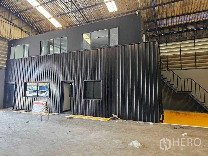 Warehouse for rent or sale in Khlong Toei, Bangkok - Close-up of the two-storey internal office suite with windows and staircase inside the warehouse.