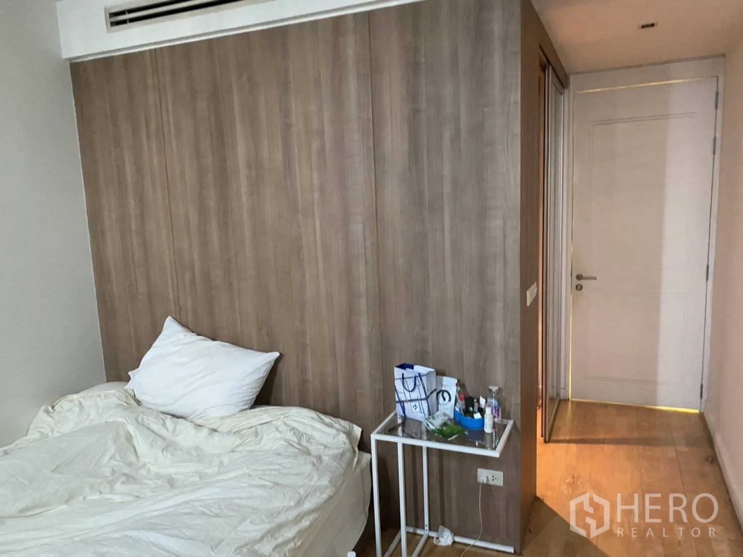 คอนโด ให้เช่าในKhlong San, Bangkok - ห้องนอนผนังไม้ เตียงผ้าปูสีขาว โต๊ะข้าง และประตูทางเดินในคอนโดกรุงเทพฯ