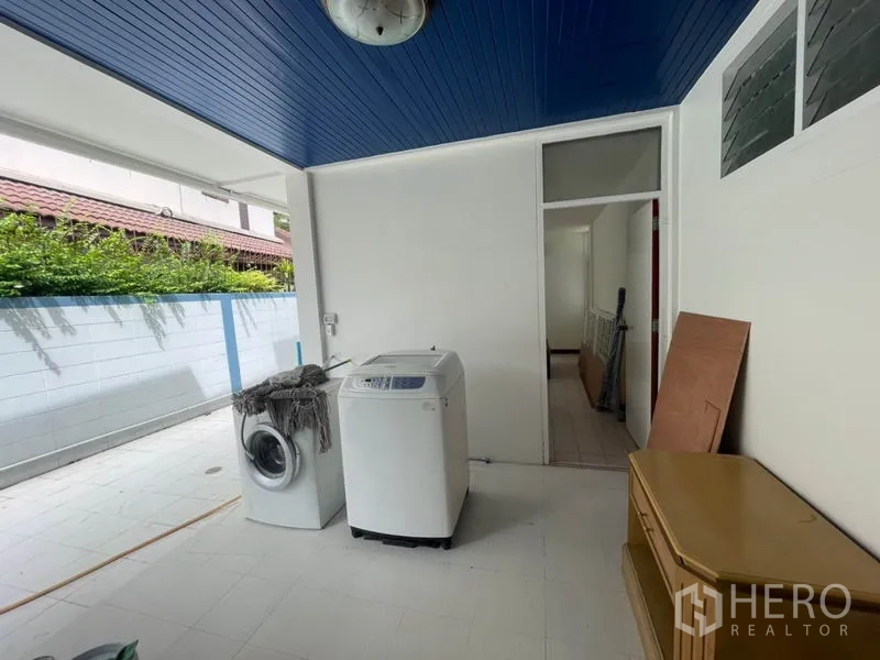 บ้าน ให้เช่าในKhlong Toei, Bangkok - โซนซักรีดและงานจิปาถะกึ่งเอาต์ดอร์ มีเครื่องซักผ้าและฝ้าเพดานสีน้ำเงิน