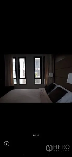 Condominium for rent in Watthana, Bangkok - Bedroom with large vertical windows, curtains and an upholstered headboard for natural light and privacy.