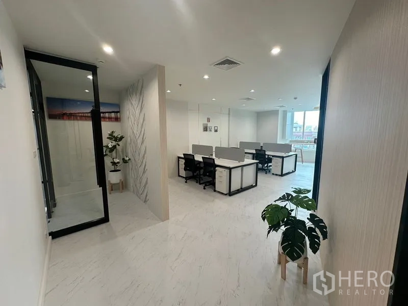 Office Space for rent - Entrance corridor with plants leading to bright open‑plan workstation area.