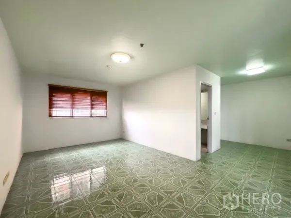 คอนโด ขายในBang Na, Bangkok - ห้องนอนพื้นกระเบื้องลายเขียว ผนังสีขาว มีมู่ลี่และทางเข้าห้องน้ำในตัว.