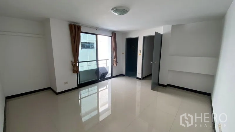 联排别墅 出租在Bang Na, Bangkok - 大卧室，亮面地砖，落地门通向小阳台。