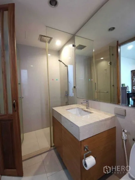 Condominium for rent or sale in Bang Rak, Bangkok - Modern bathroom featuring a glass-enclosed rain shower and a stone-topped vanity.