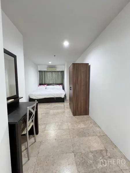 Condominium for rent in Ratchathewi, Bangkok - Long bedroom layout featuring a desk, wardrobe and tiled flooring.