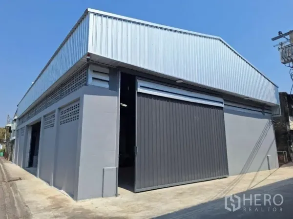 Warehouse for rent in Rat Burana, Bangkok - Corner view of renovated warehouse exterior with metal cladding and large sliding door in Rat Burana, Bangkok.