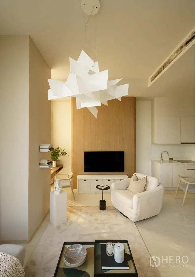 Condominium for rent in Bang Rak, Bangkok - Bright living space with sculptural chandelier, TV console, and built-in work desk.