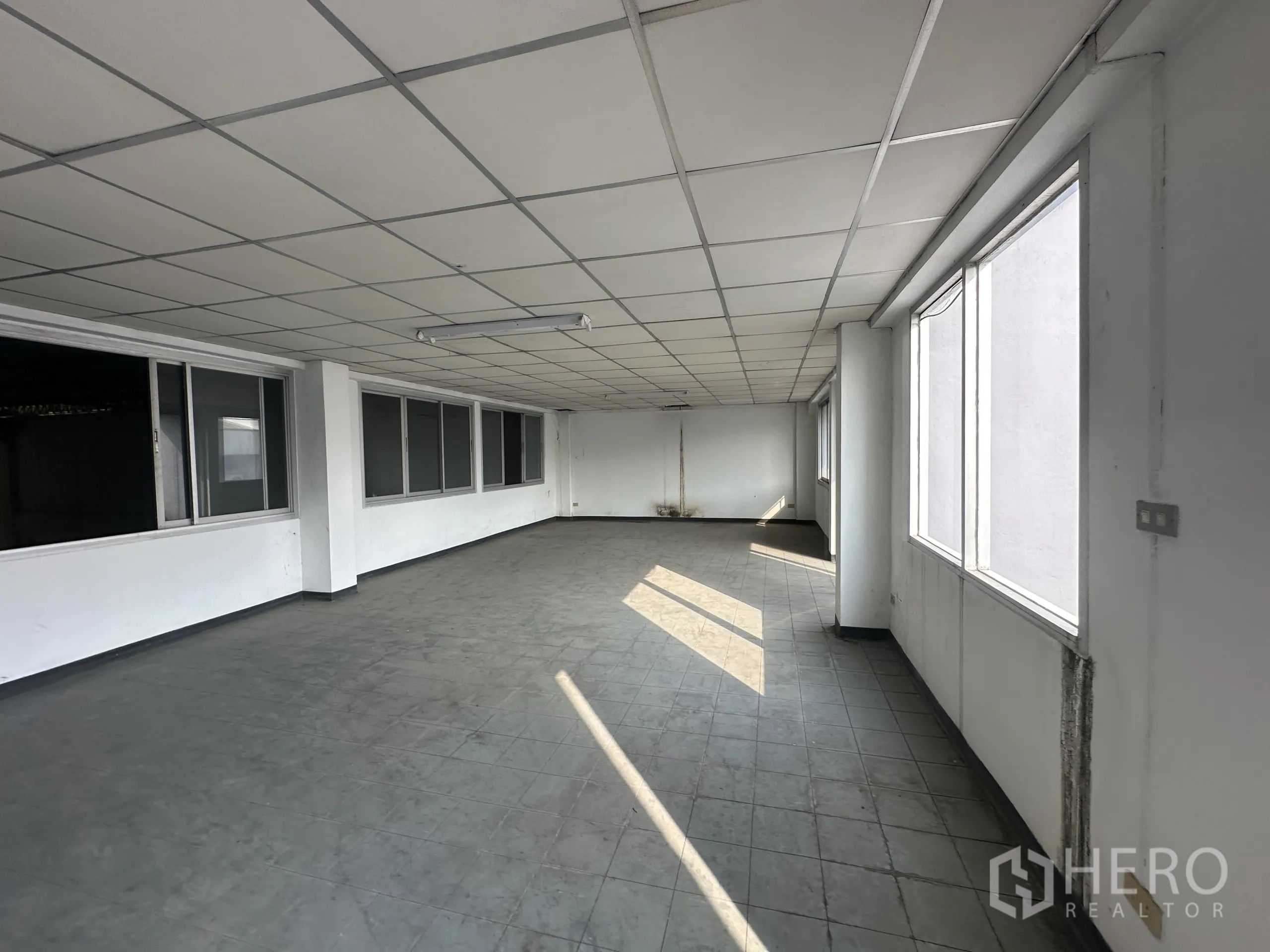 Factory for rent or sale in Khlong Luang, Pathum Thani - Bright office area with grid ceiling, multiple windows and grey tile floor suitable for workstations.