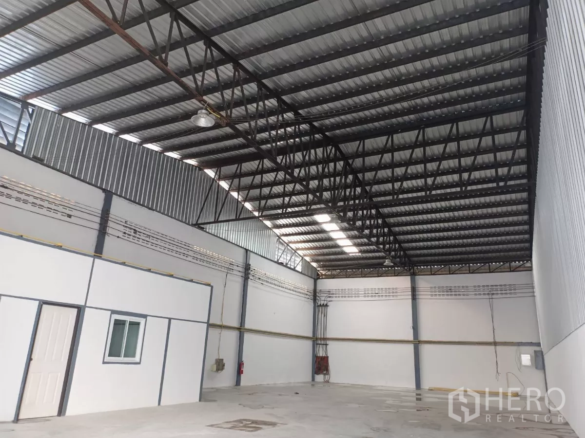 Warehouse for rent in Suan Luang, Bangkok - High clear-span steel roof with skylight panels above the warehouse interior beside the office unit.