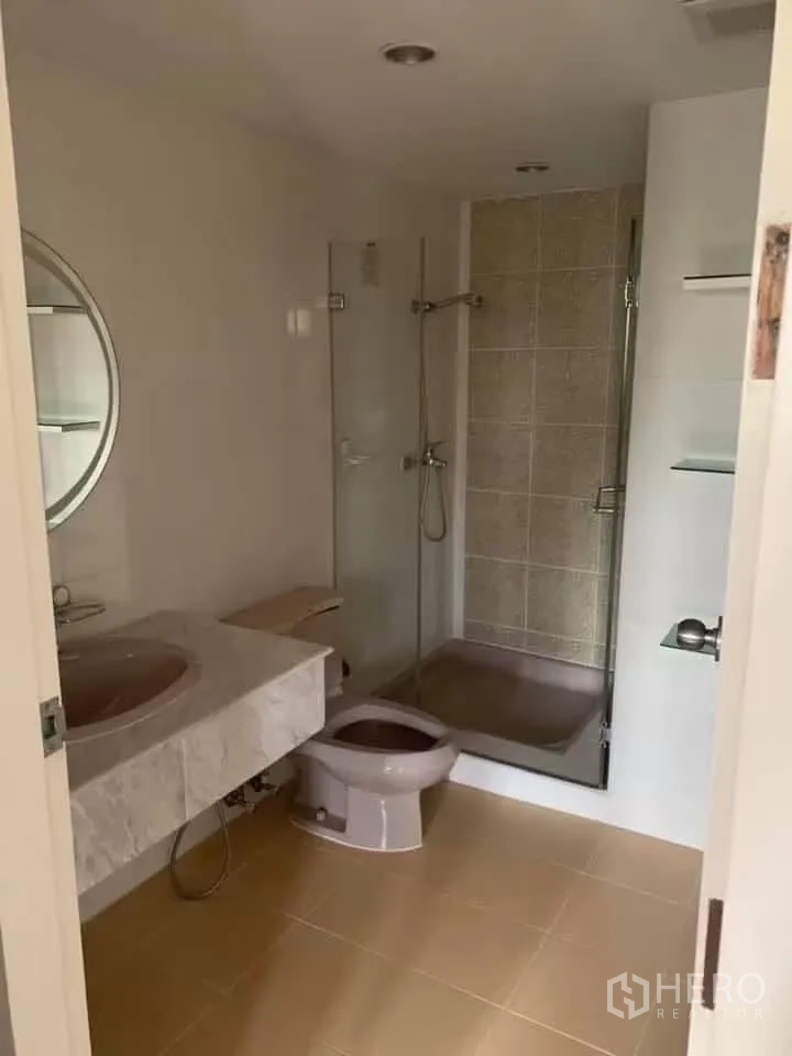 Townhouse for rent in Watthana, Bangkok - Bathroom with glass-enclosed shower, vanity, and toilet.