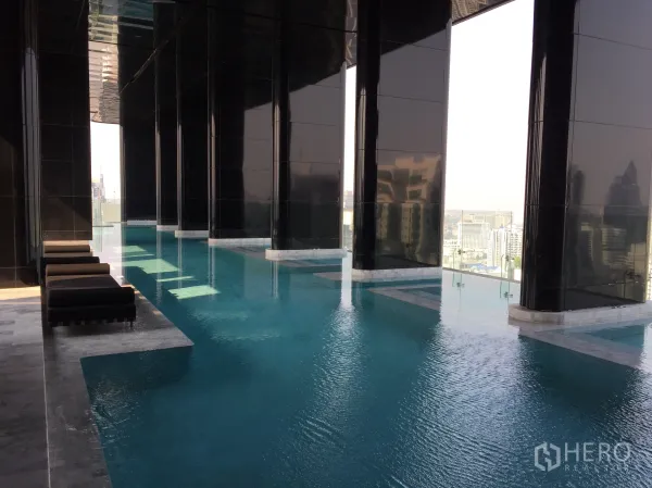คอนโด ขายในWatthana, Bangkok - สระว่ายน้ำอินฟินิตี้ในอาคารสูง พร้อมเตียงพักผ่อนและวิวเมืองกว้าง