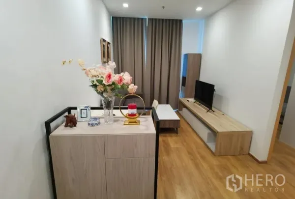 คอนโด ให้เช่าในWatthana, Bangkok - โถงทางเข้าพร้อมชั้นวางทีวี โต๊ะกลาง และของตกแต่ง บนพื้นไม้โทนอุ่น