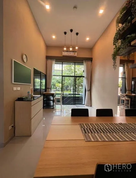Townhouse for rent in Yan Nawa, Bangkok - Dining area facing greenery with pendant lights and full-height sliding doors.