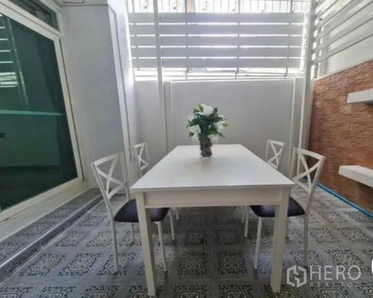 联排别墅 出租在Prawet, Bangkok - 半户外用餐区，白色餐桌四把椅子，带私密百叶屏风。