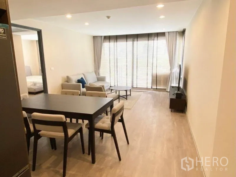 Condominium for rent in Pathum Wan, Bangkok - Living-dining area view toward balcony with sofa set, media unit and dining table.