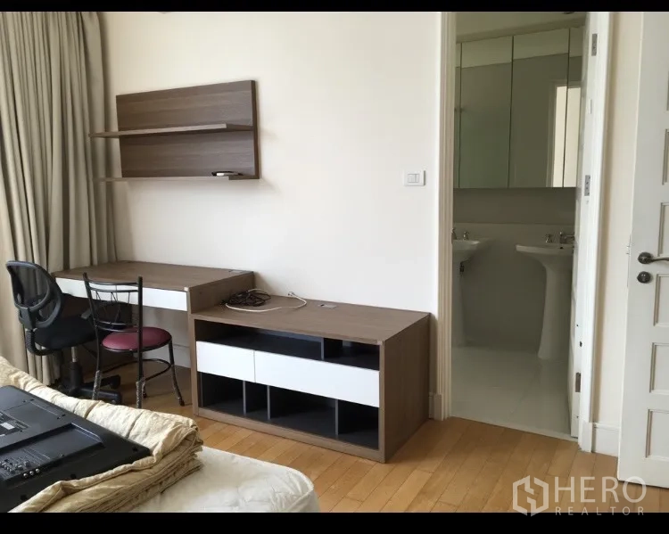 Condominium for rent in Khlong Toei, Bangkok - Workstation with desk, chair, wall shelves and TV console facing a bright bathroom.
