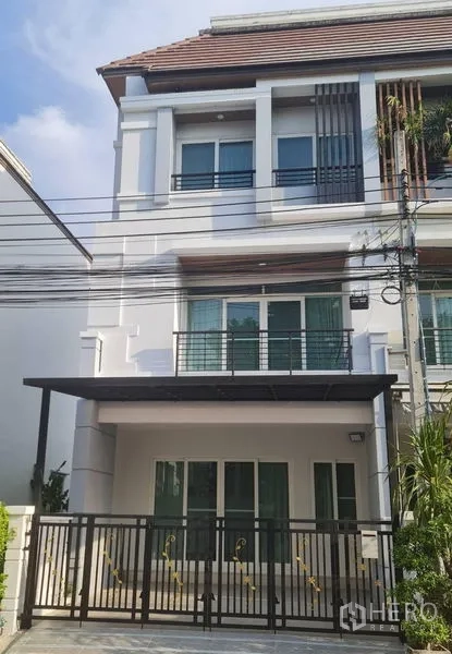 联排别墅 出租在Prawet, Bangkok - 三层现代联排别墅外立面，带阳台、白色外墙与带门车位。