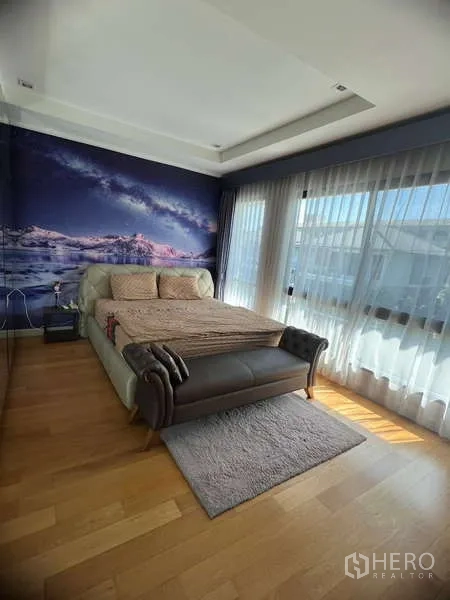独立式住宅 出租或出售在Prawet, Bangkok - 主卧室，环绕落地窗与特色壁画，床尾长凳