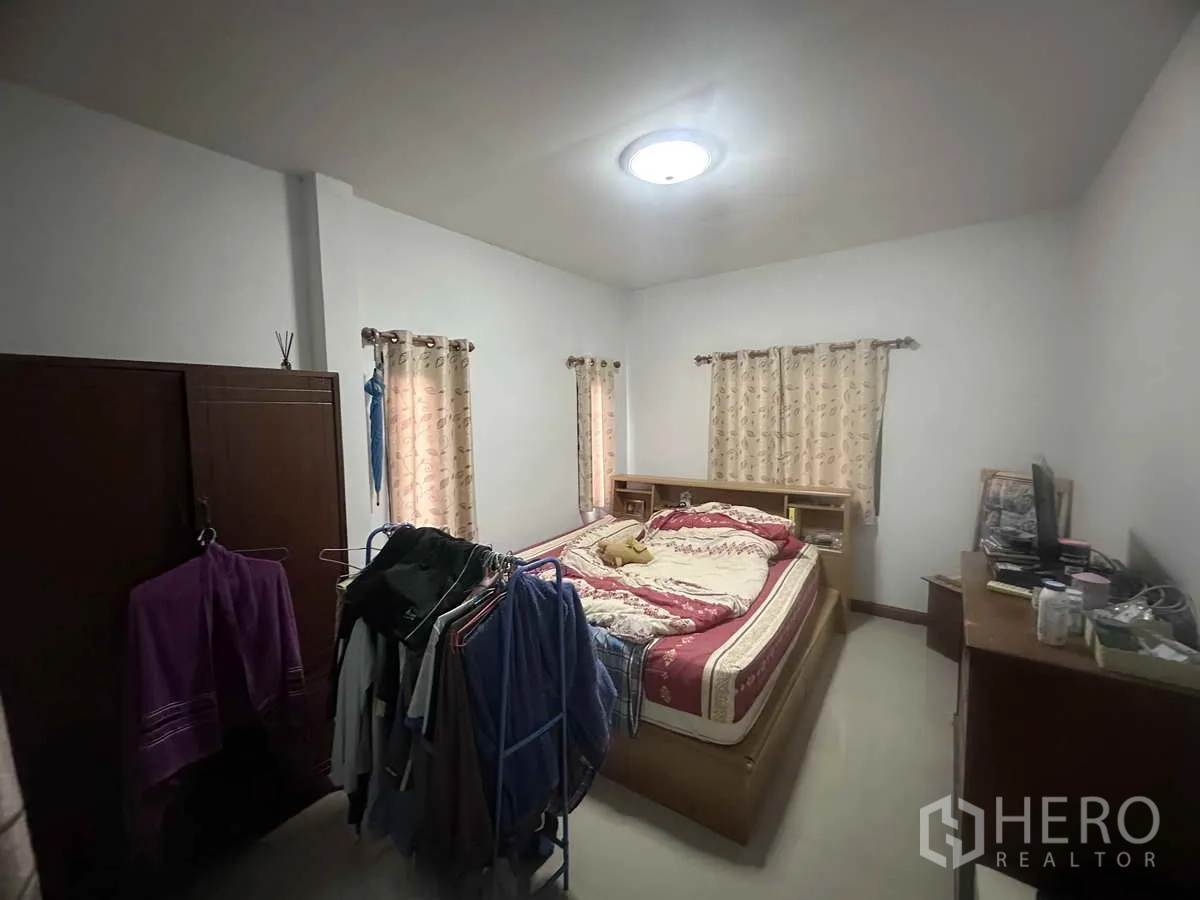 独立式住宅 出售在Pathum Thani - 宽敞主卧，双人床、衣柜和衣架。