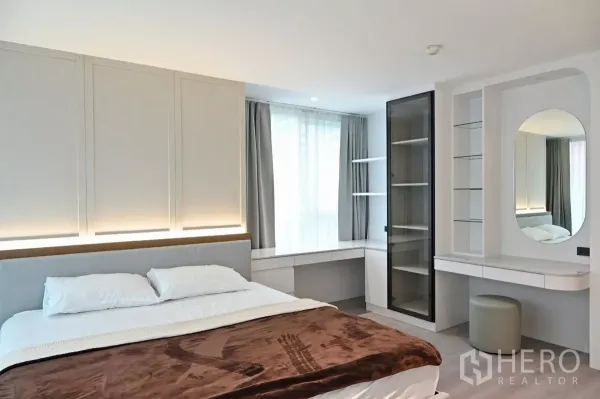Condominium for rent in Watthana, Bangkok - Bright secondary bedroom with large window, built-in shelving and vanity desk in the Bangkok condo.
