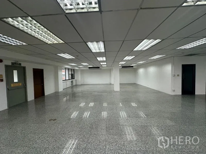 สำนักงาน ให้เช่า - โซนสำนักงานสว่างไสว มีประตูทางหนีไฟ หน้าต่างหลายบาน และไฟฝ้าทีบาร์