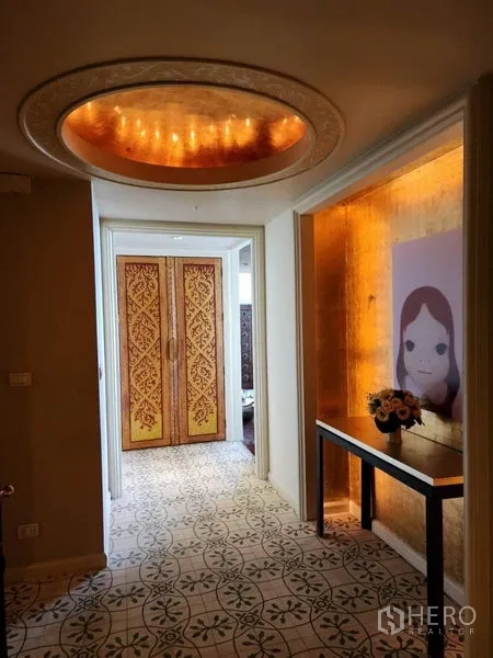 Condominium for rent in Bang Rak, Bangkok - Bright hallway with patterned tiles, gold accent wall, and carved double doors beneath a dome light.