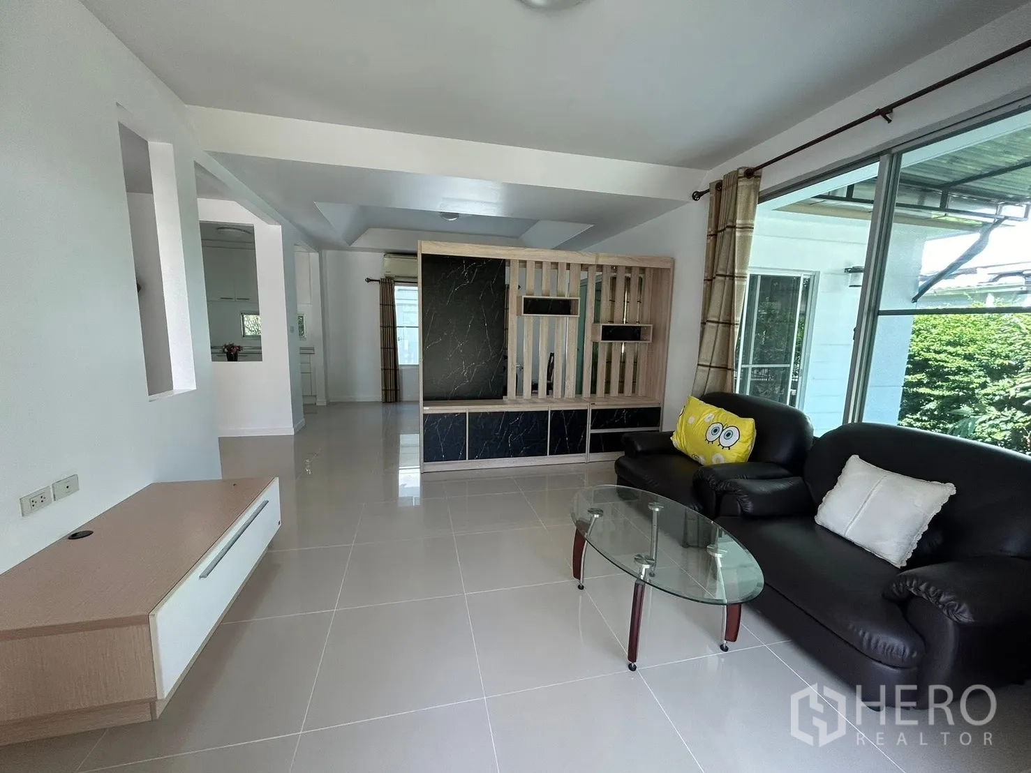 独栋房屋 for rent in Bang Na, Bangkok - 开放式客厅配皮沙发、玻璃茶几与大窗户。