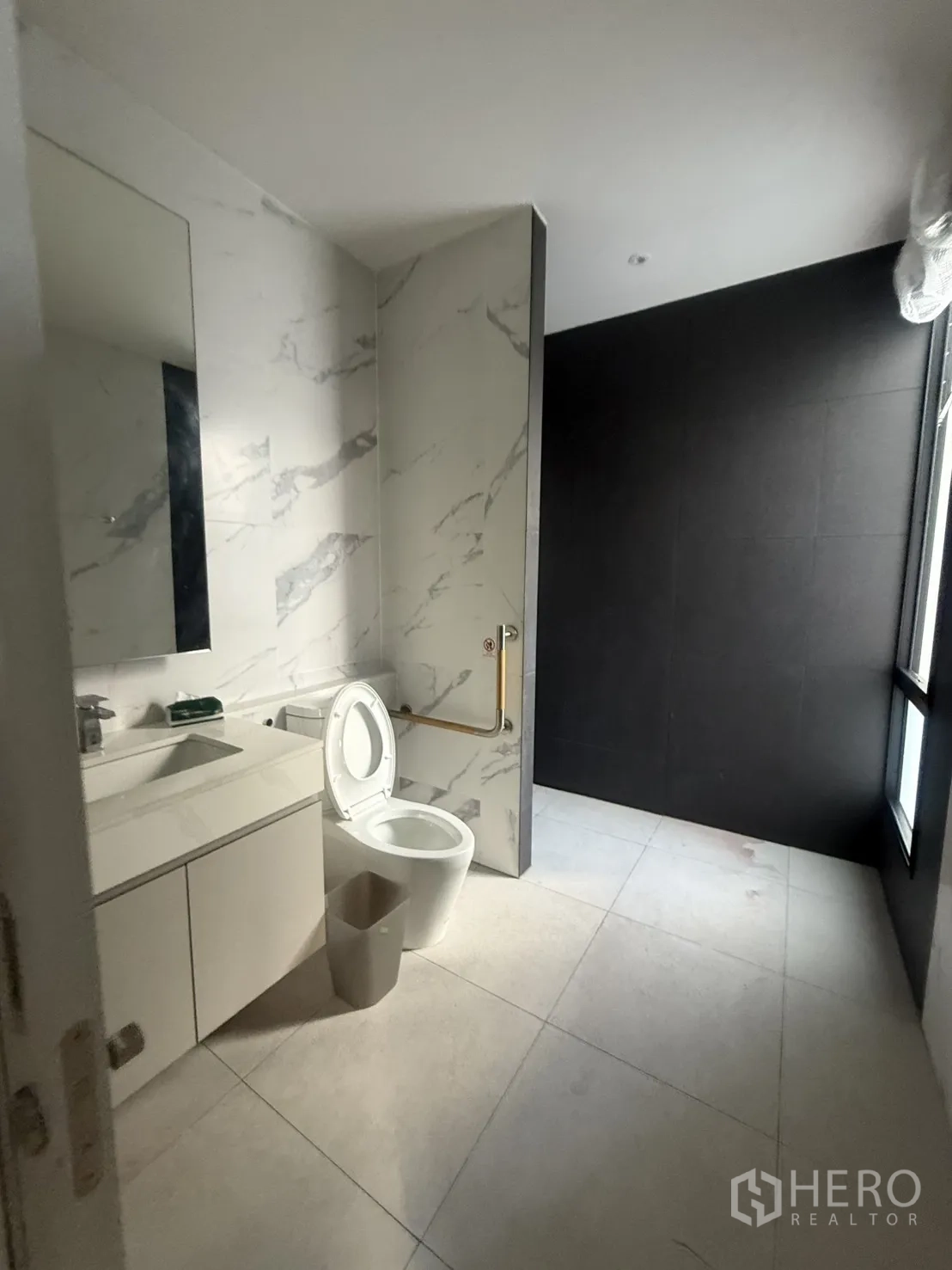 Detached House for rent in Saphan Sung, Bangkok - Spacious bathroom with white marble tiles, vanity and walk-in shower.