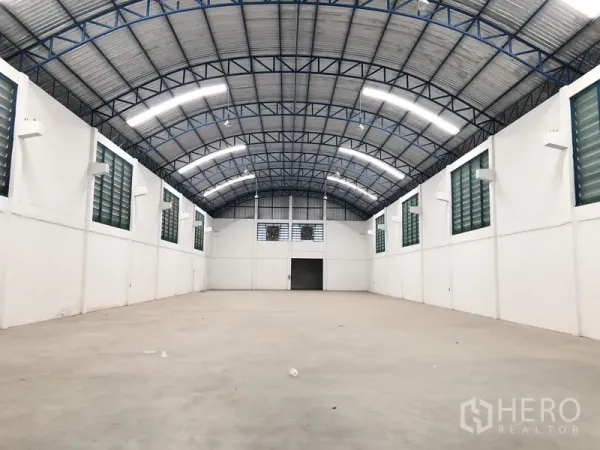 Factory for rent or sale in Bang Sao Thong, Samut Prakan - Open factory floor with high clearance, louvered ventilation windows, and a large entry door.