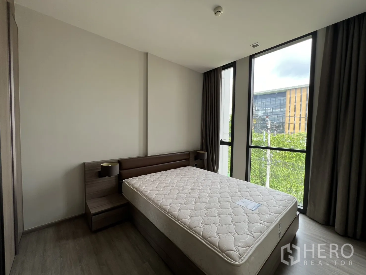 Condominium for rent in Watthana, Bangkok - Bedroom with a double bed, large windows, and views of greenery.