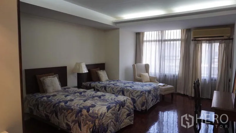 房间 出租在Khlong Toei, Bangkok - 次卧设两张单人床、休闲椅与大窗户，天花隐藏灯带柔和。