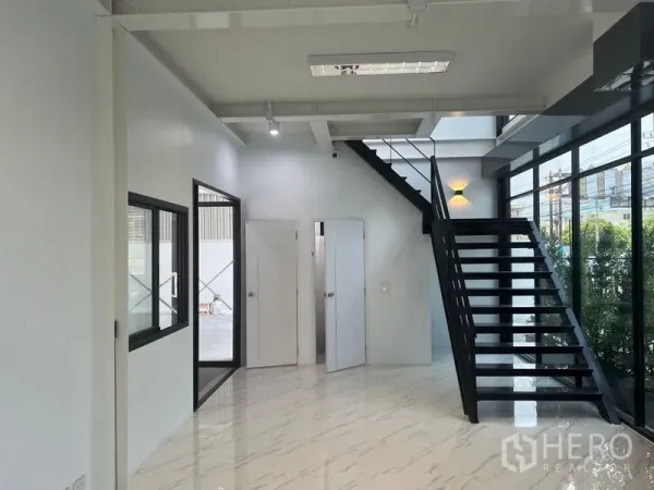 货栈 出租在Bang Sao Thong, Samut Prakan - 一层办公室大堂，黑色钢梯、白墙及多间内部门。