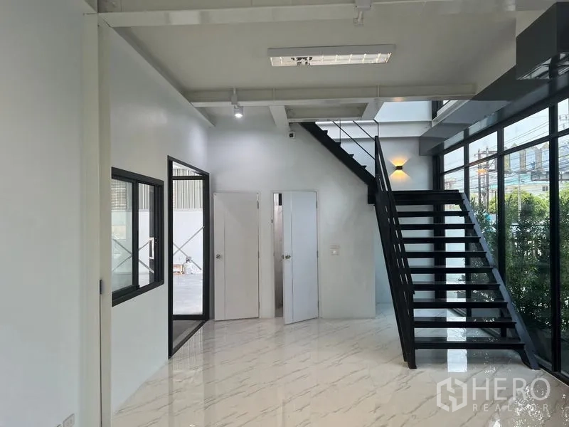 货栈 出租在Bang Sao Thong, Samut Prakan - 一层办公室大堂，黑色钢梯、白墙及多间内部门。