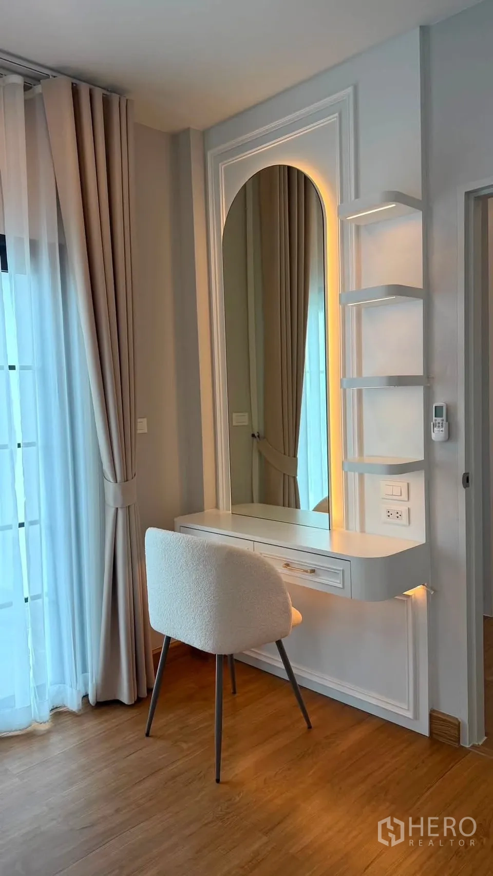 บ้านเดี่ยว for rent or sale in Bang Phli, Samut Prakan - มุมโต๊ะเครื่องแป้งติดกระจกโค้งพร้อมชั้นวางและเก้าอี้ข้างผ้าม่านโปร่งแสง
