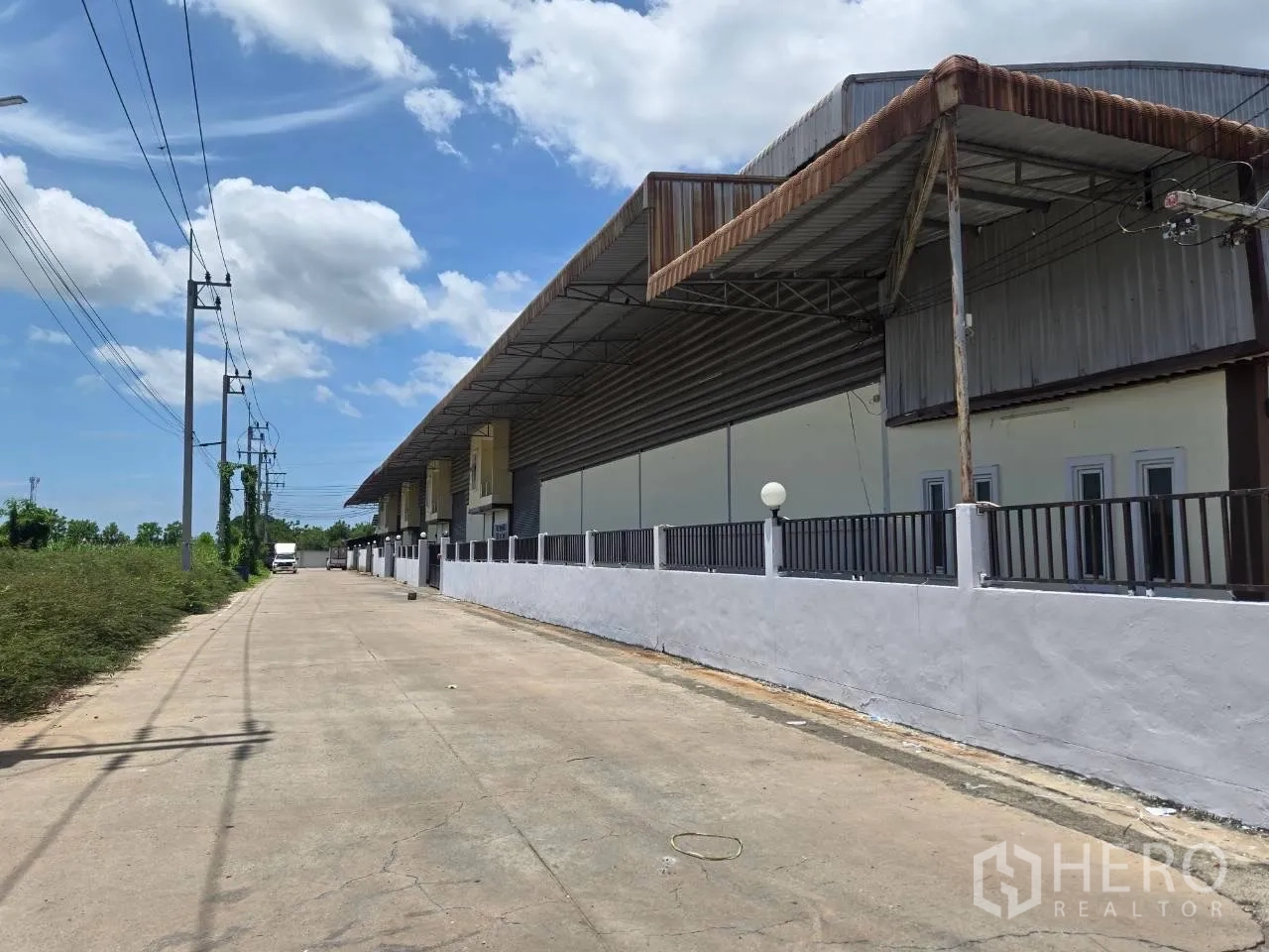 โกดัง for rent or sale in Mueang Samut Sakhon, Samut Sakhon - ด้านหน้าโกดังแสดงกันสาดยาวและรั้วตลอดแนวถนน