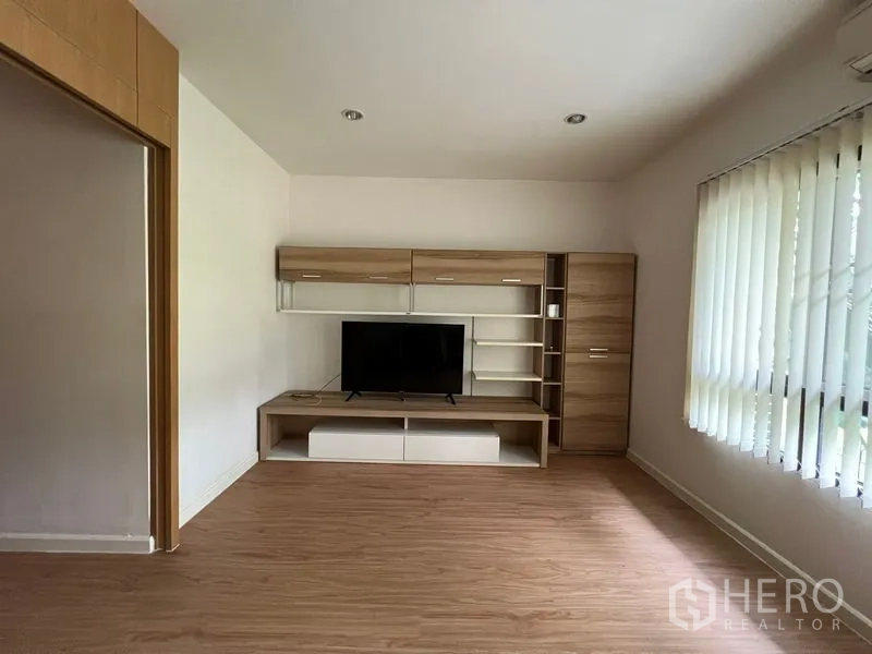 Townhouse for rent in Bang Kapi, Bangkok - TV wall with shelving unit in bright living space.