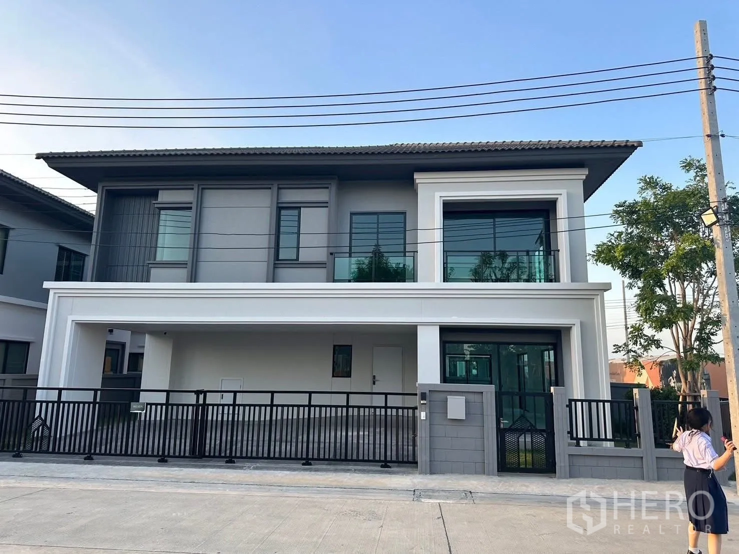 บ้านเดี่ยว for rent in Bang Phli, Samut Prakan - ด้านหน้าบ้านเดี่ยวสองชั้นสไตล์โมเดิร์น มีระเบียงกระจก ประตูรั้ว และที่จอดรถในร่ม