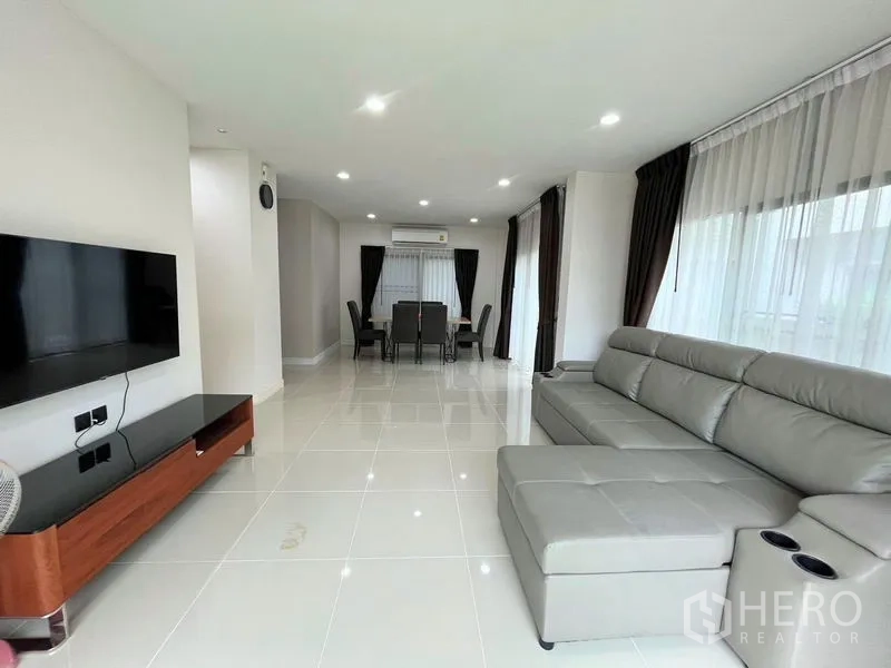 Detached House for rent in Bang Kapi, Bangkok - Open-plan living and dining area with large sofa, TV and floor-to-ceiling windows