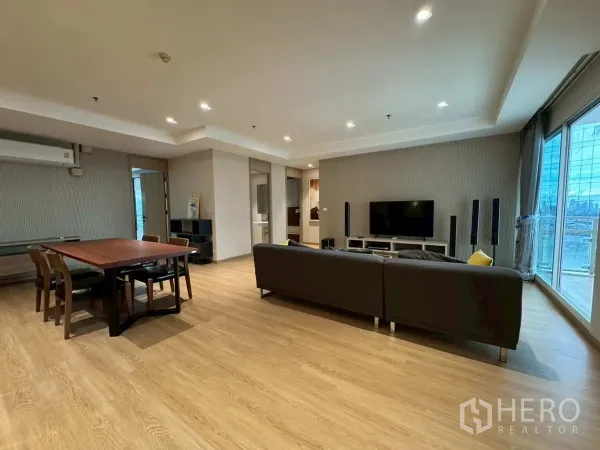 Condominium for rent or sale in Khlong Toei, Bangkok - Wide living–dining room with TV console and floor-to-ceiling windows.