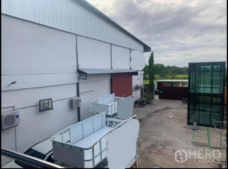 คลังสินค้า ให้เช่าในSai Noi, Nonthaburi - มุมมองจากชั้นบนเห็นลานขนถ่าย โกดัง ประตูสีแดง และประตูรั้วติดทุ่งเขียว