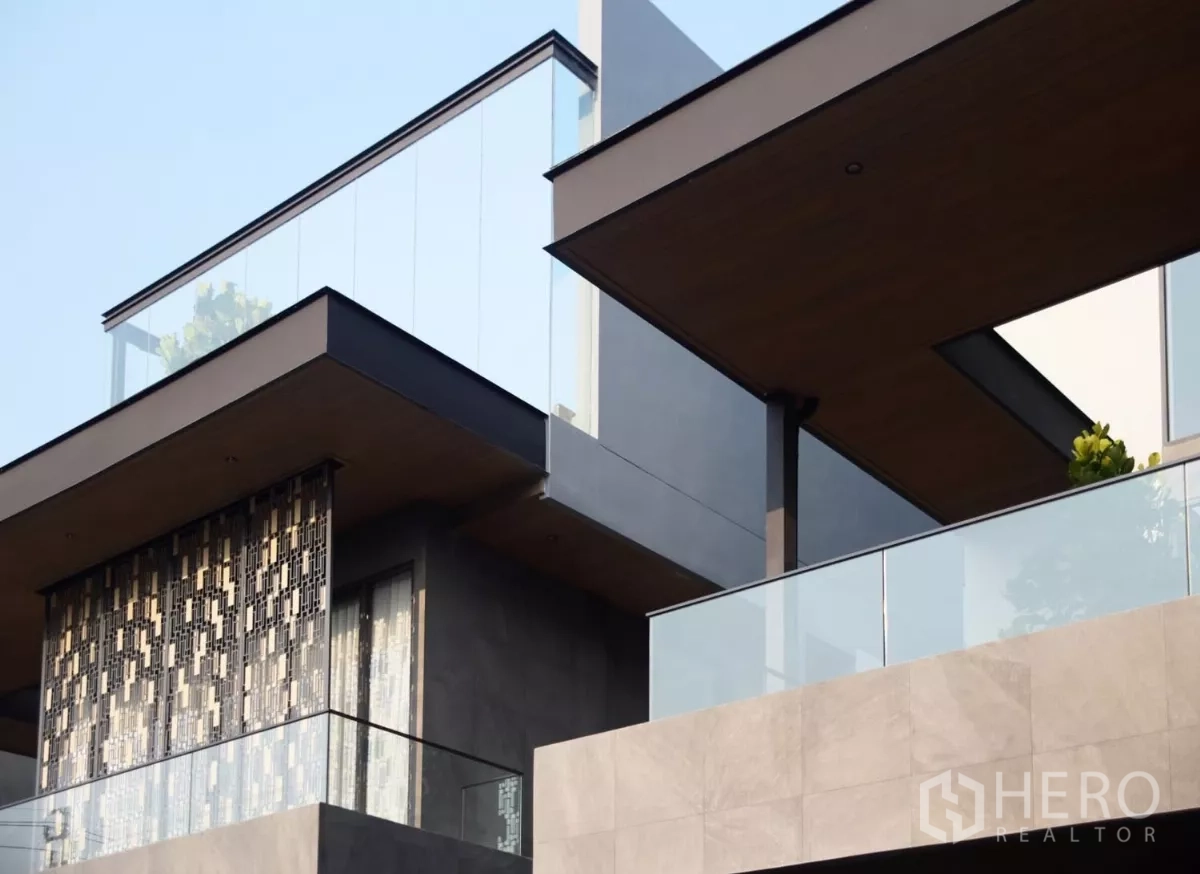 บ้าน ขายในLat Phrao, Bangkok - ด้านหน้าบ้านเดี่ยวสไตล์โมเดิร์นในลาดพร้าว พร้อมระเบียงกระจกและฝ้าไม้โทนอุ่น