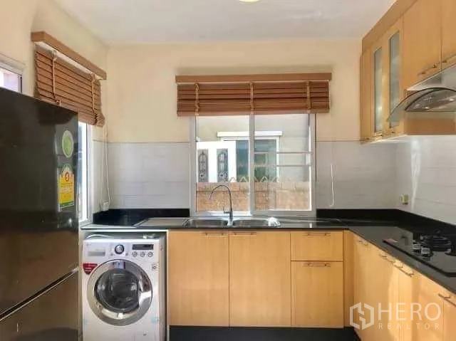 Detached House for rent in Bang Phli, Samut Prakan - Kitchen view showing refrigerator, washer, range hood and windows with wooden blinds.
