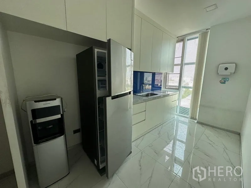 Office Space for rent - Pantry with white cabinetry, stainless refrigerator, sink and water dispenser by a tall window.