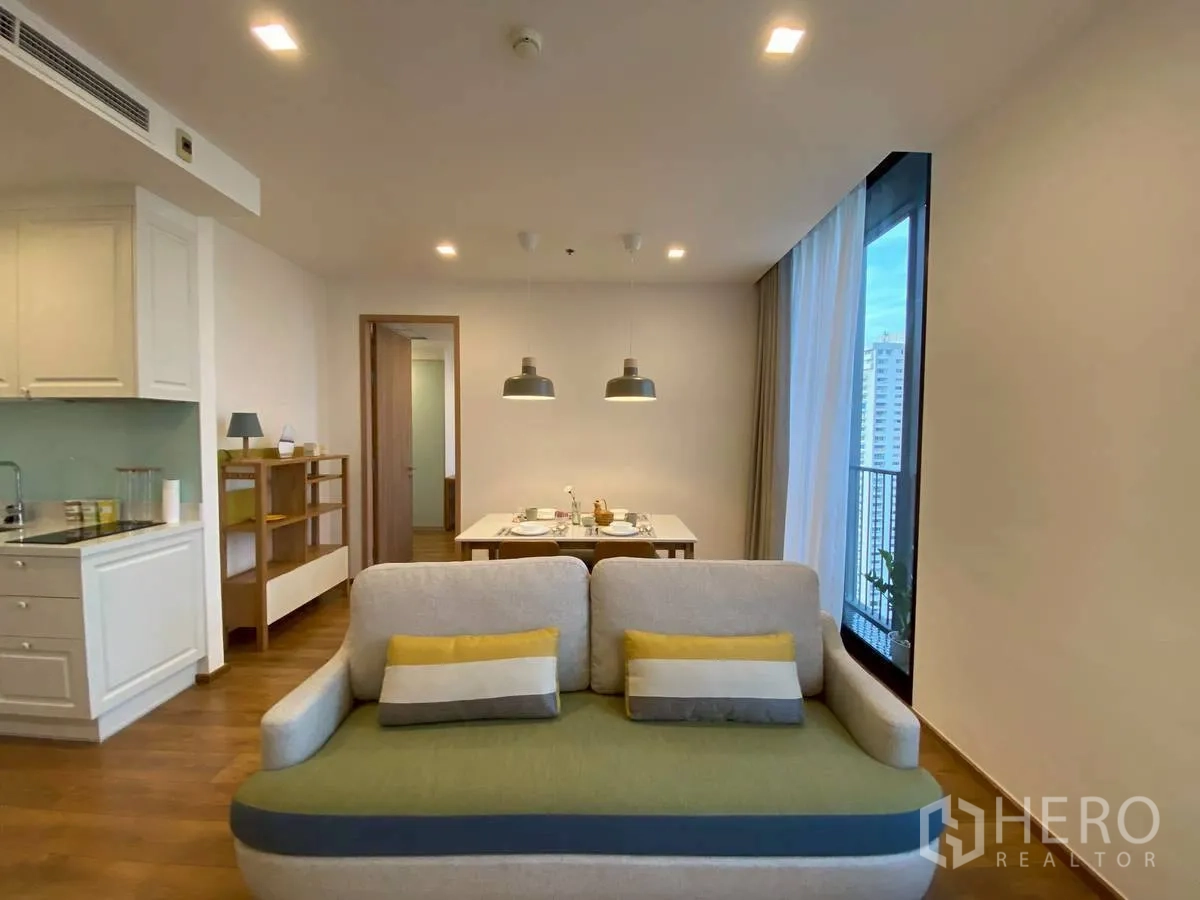 Condominium for rent in Watthana, Bangkok - Open-plan living and dining area beside the kitchen with tall windows.