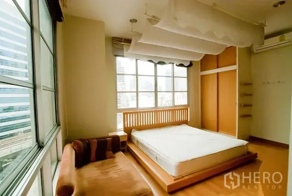 公寓 出租在Khlong Toei, Bangkok - 明亮卧室，落地窗、平台床、衣柜，可观城市天际线。