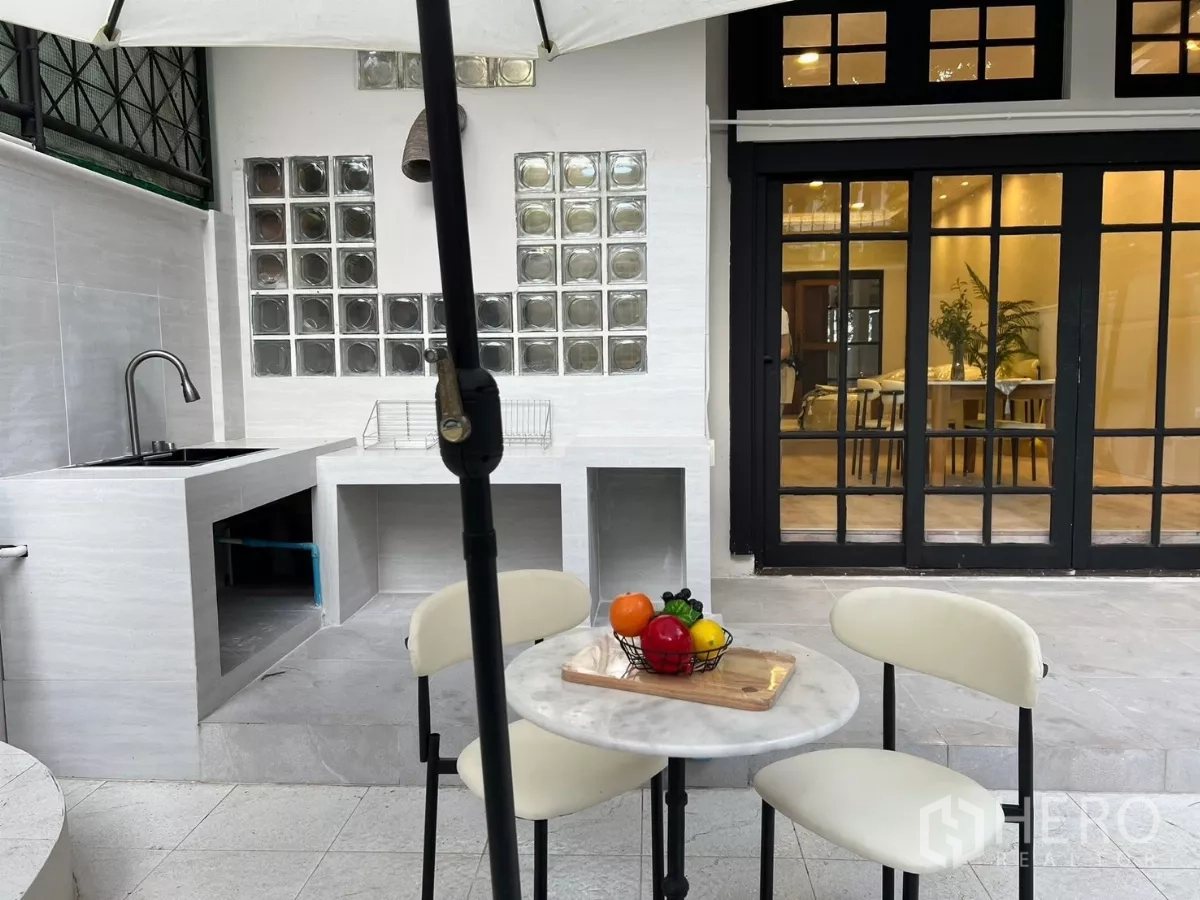 Townhouse for rent - Outdoor wet kitchen with sink, tiled counters and black-framed sliding doors to the house.