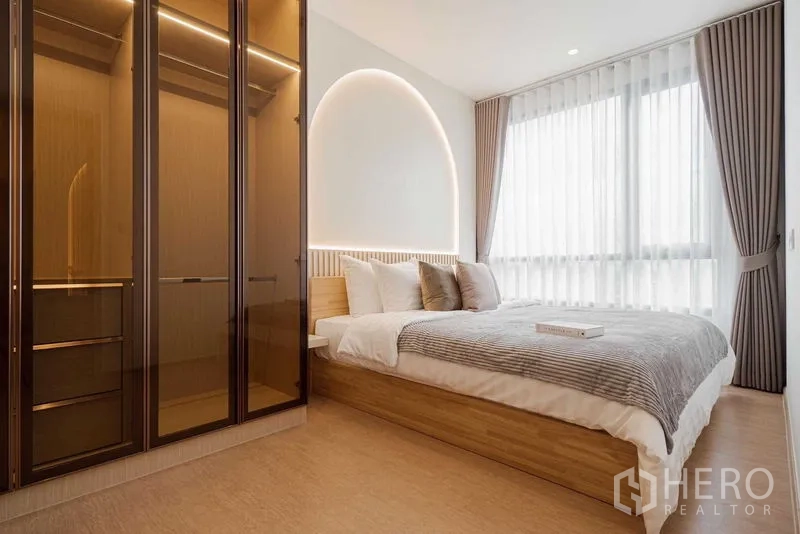 Condominium for rent in Watthana, Bangkok - Master bedroom with arched LED headboard, floor-to-ceiling window and glass wardrobe.